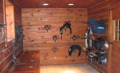 A cedar lined horse tack room with saddles and bridles on the wall.
